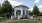 a white building with a large front yard and trees